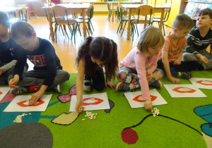 Dzieci układają ziarna fasoli na szablonie ust.